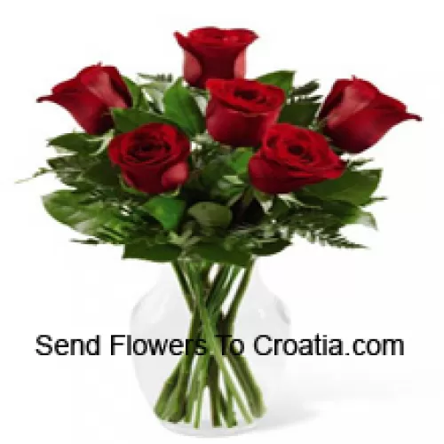 7 красных роз с папоротниками в стеклянной вазе