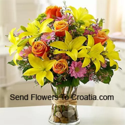 Желтые лилии, оранжевые розы и розовые герберы с сезонными наполнителями в стеклянной вазе