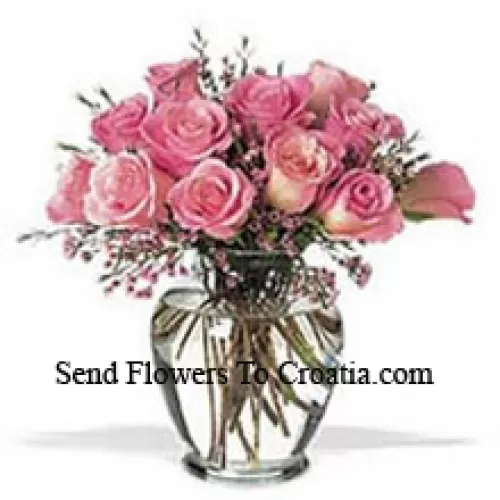 Tros van 11 roze rozen met wat varens in een vaas